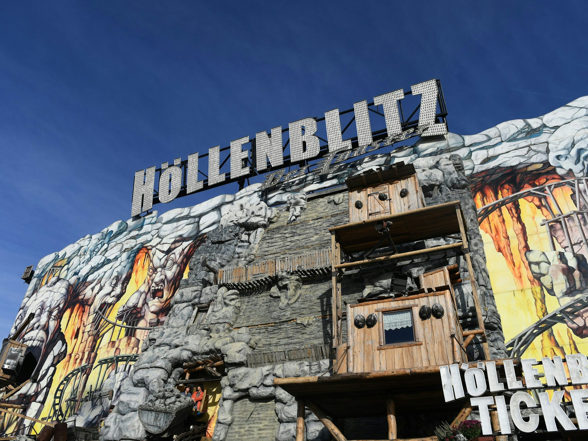 Blauer Himmel strahlt über dem Fahrgeschäft „Höllenblitz“ auf dem Münchner Oktoberfest.