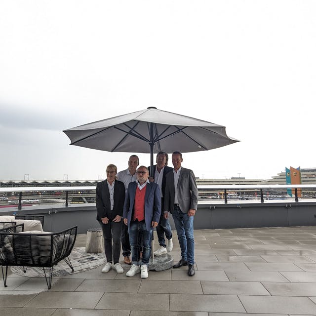 Gruppenbild auf einer Terrasse, im Hintergrund der Kölner Flughafen