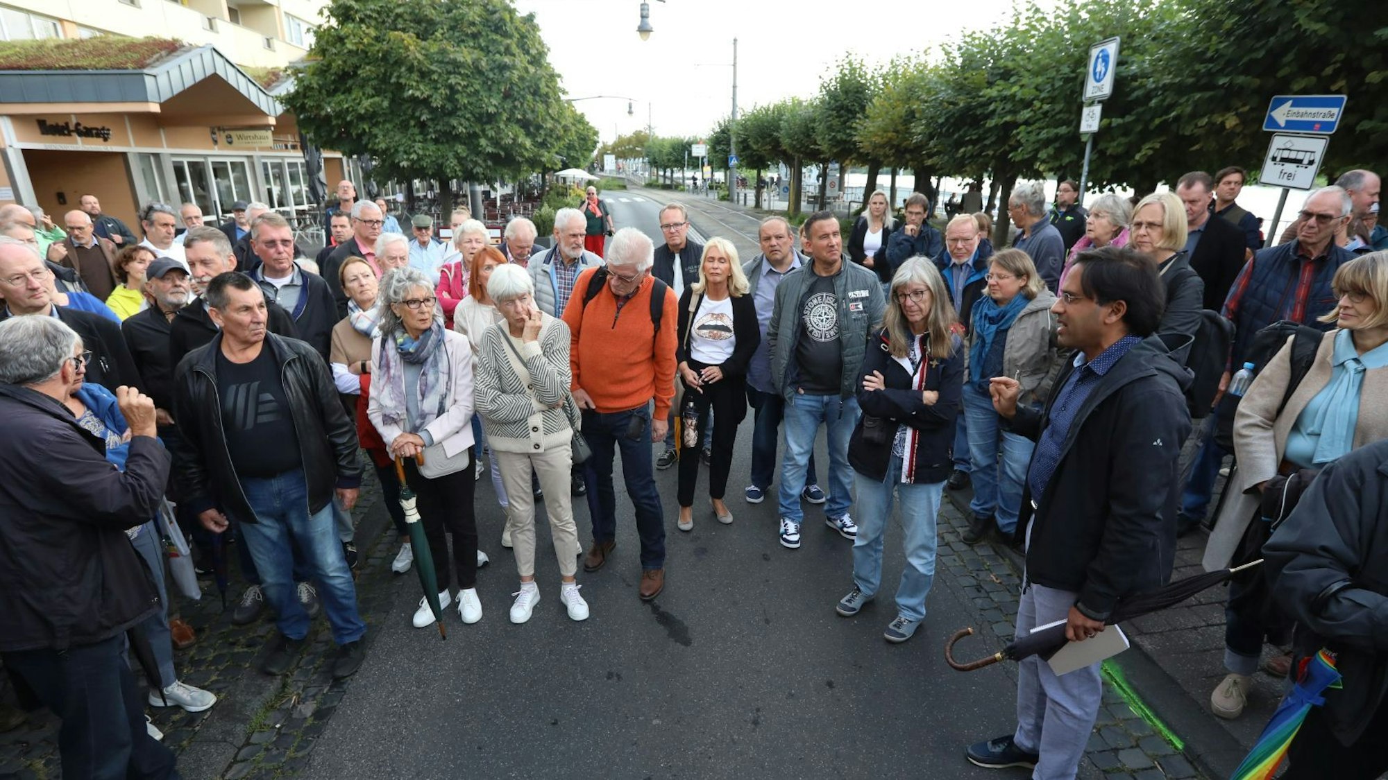 Eine Gruppe von Menschen steht auf der Rheinallee und der Stadtbahntrasse in der Altstadt von Königswinter.