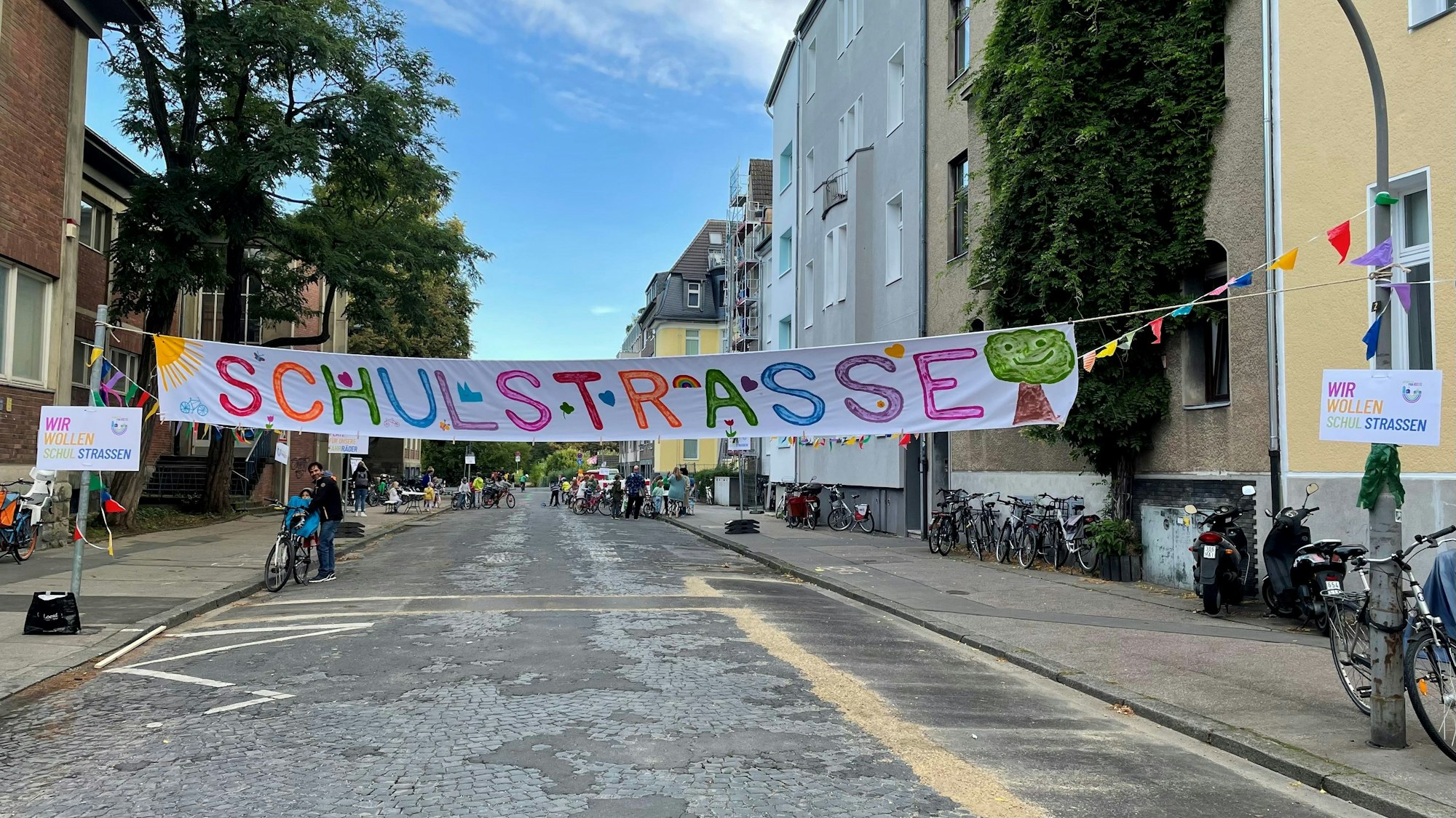 Die Kretzerstraße mit einem großen Banner, auf dem in bunten Lettern „Schulstraße“ steht