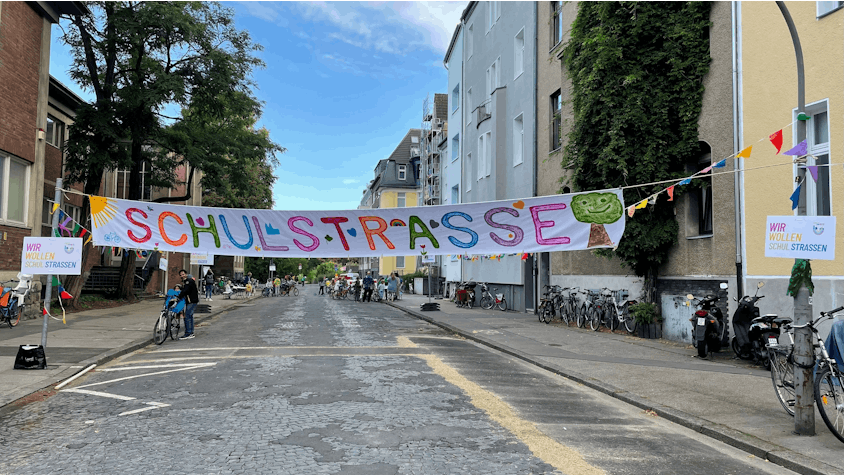 Banner „Schulstraße“ über einer Straße in Köln.
