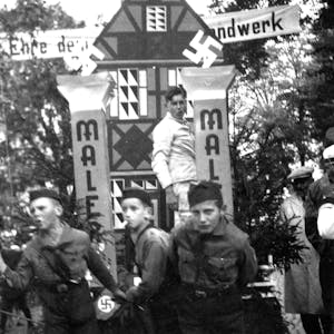 Drei Jungen in Uniformen der Hitlerjugend ziehen einen Wagen.