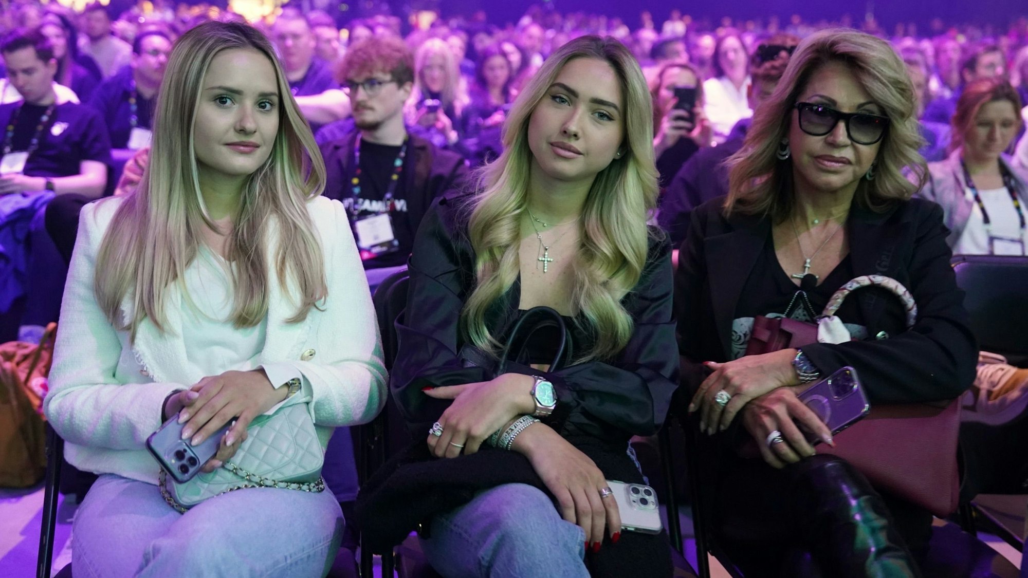 Davina (l-r) und Shania Geiss sitzen neben ihrer Mutter Carmen Geiss während des Auftritts von Robert Geiss, Unternehmer und TV-Reality-Star, auf der Bühne der Digital-Messe OMR in den Messehallen.