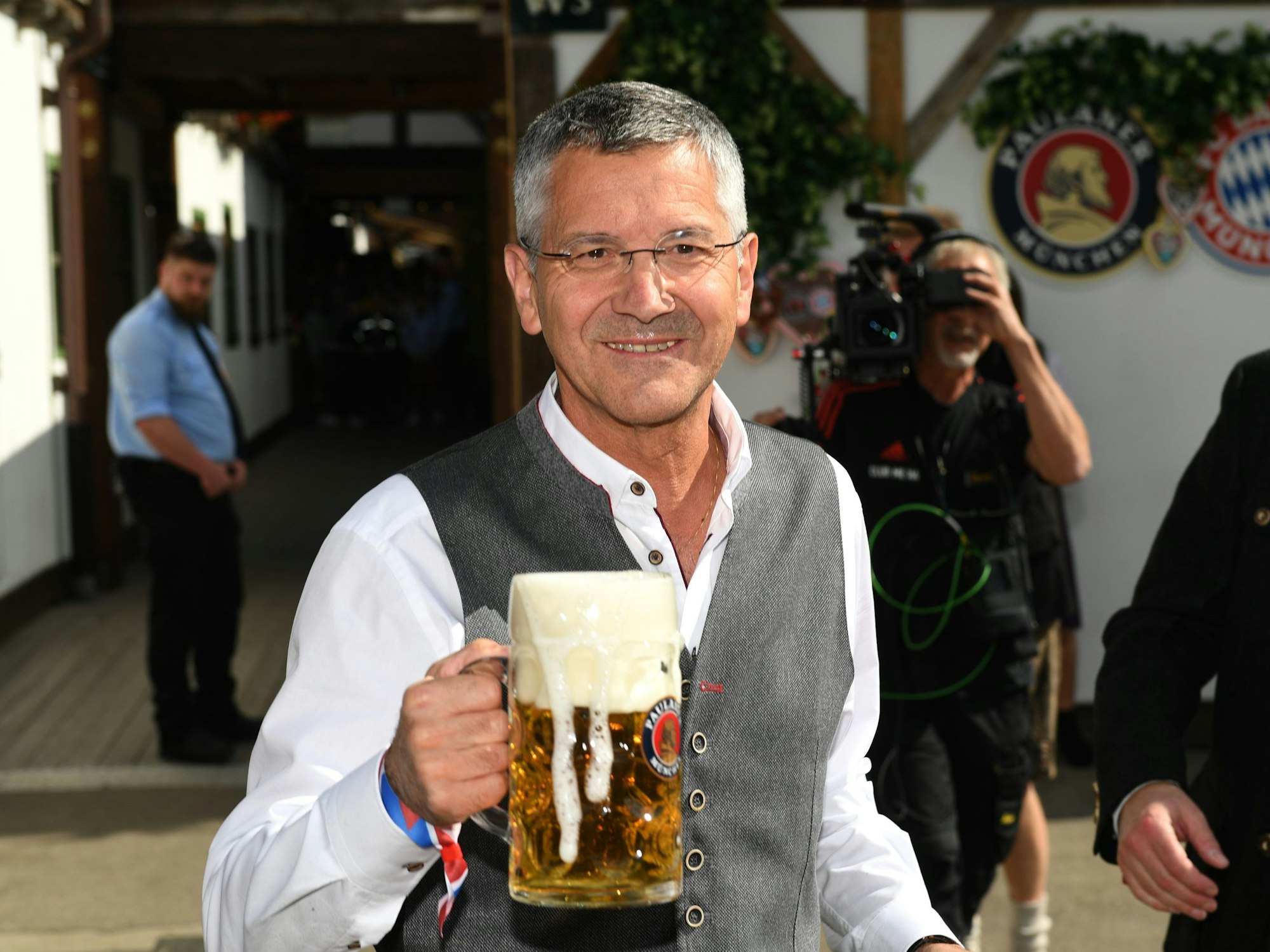 Herbert Hainer, Präsident des FC Bayern München, steht mit einer Maß Bier vor dem Käferzelt.