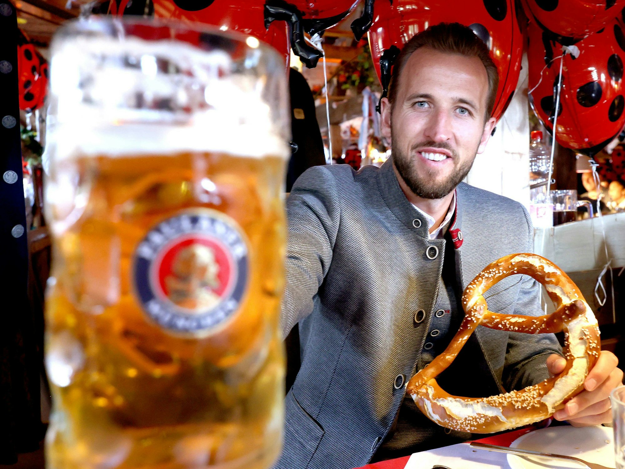 Harry Kane vom FC Bayern München sitzt mit einer Maß Bier und einer Brezn im Käferzelt.