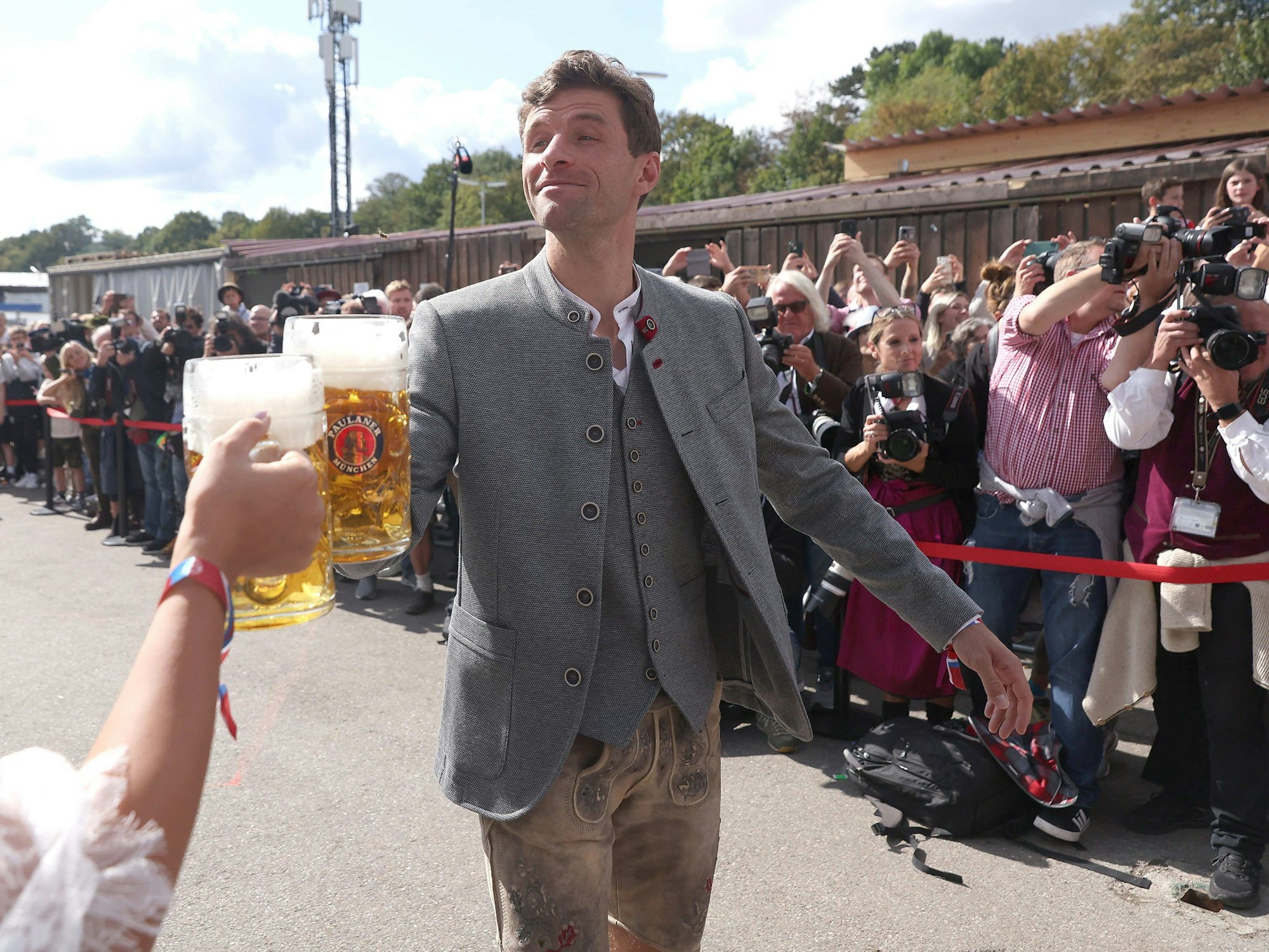 Thomas Müller vom FC Bayern München kommt mit einer Maß Bier zum Käferzelt.