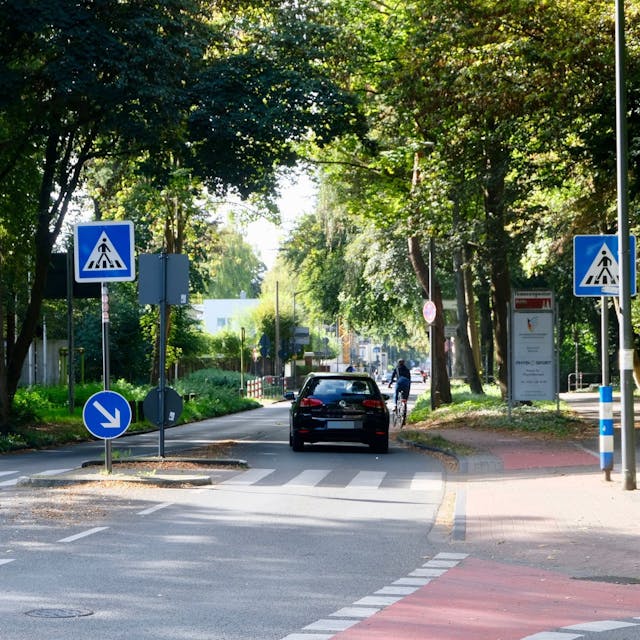 Eine Straße wird von einem Auto und einem Fahrrad befahren.
