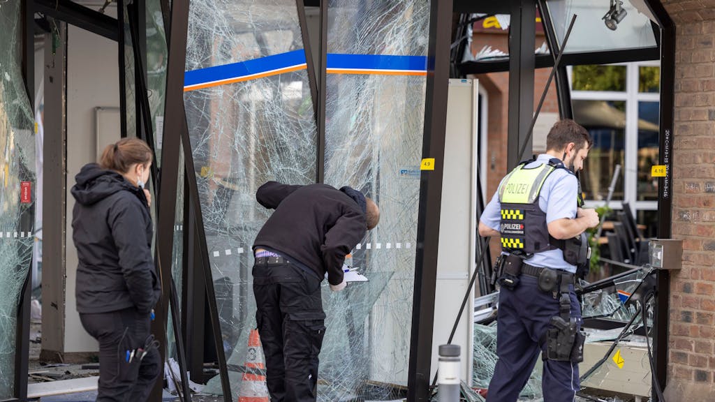 Einsatzkräfte der Polizei untersuchen den Eingang eine Bank, der nach einer Geldautomatensprengung zerstört wurde.&nbsp;