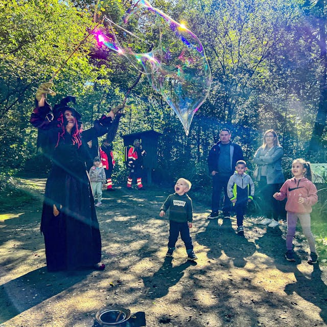 Eine Hexe verzaubert Kinder mit risigen Seifenblasen