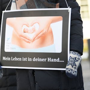 Hessen, Frankfurt am Main: Mit Plakaten mit der Aufschrift „Mein Leben ist in deiner Hand...“ und dem Bild eines 10 Wochen alten Embryo demonstrieren Abtreibungsgegner von der „Aktion SOS Leben“ vor der Beratungsstelle von Pro Familia. Ihr Protest richtet sich gegen die Schwangerschaftskonfliktberatung, die die Organisation in gesetzlichem Auftrag durchführt.&nbsp; Foto: Arne Dedert/dpa +++ dpa-Bildfunk +++ (Archivbild/Symbolbild)