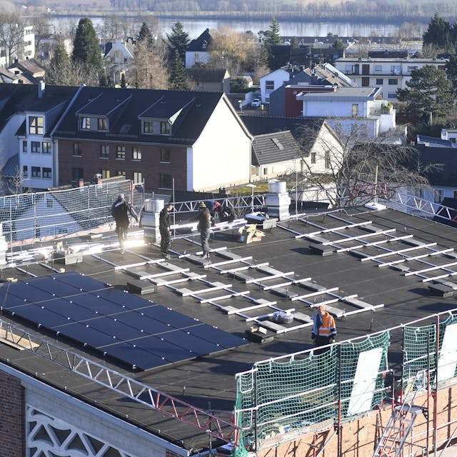 Bauarbeiter installieren Solarmodule auf dem Dach einer Kirche.