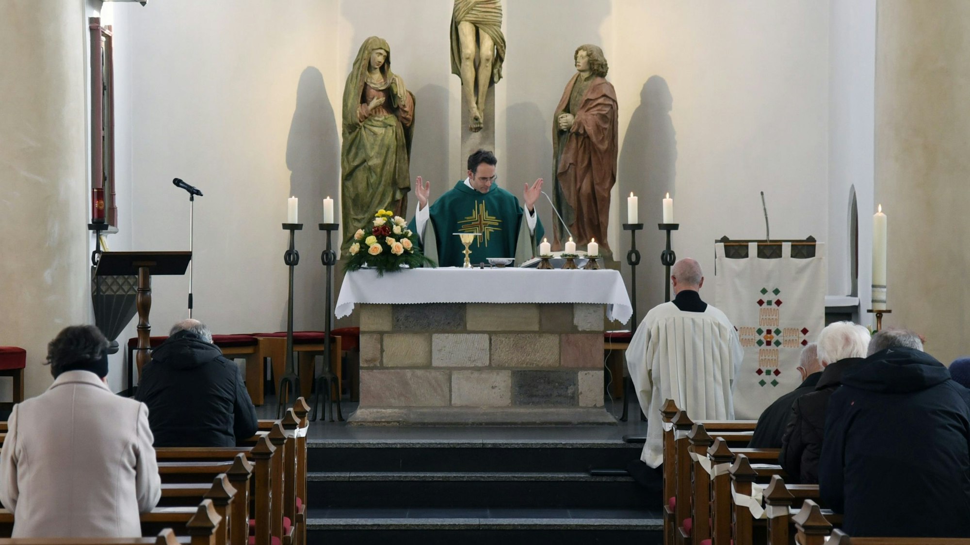 Pastor Martin Reimer steht mit ausgebreiteten Armen hinter dem Altar der katholischen Pfarrkirche St. Severin.