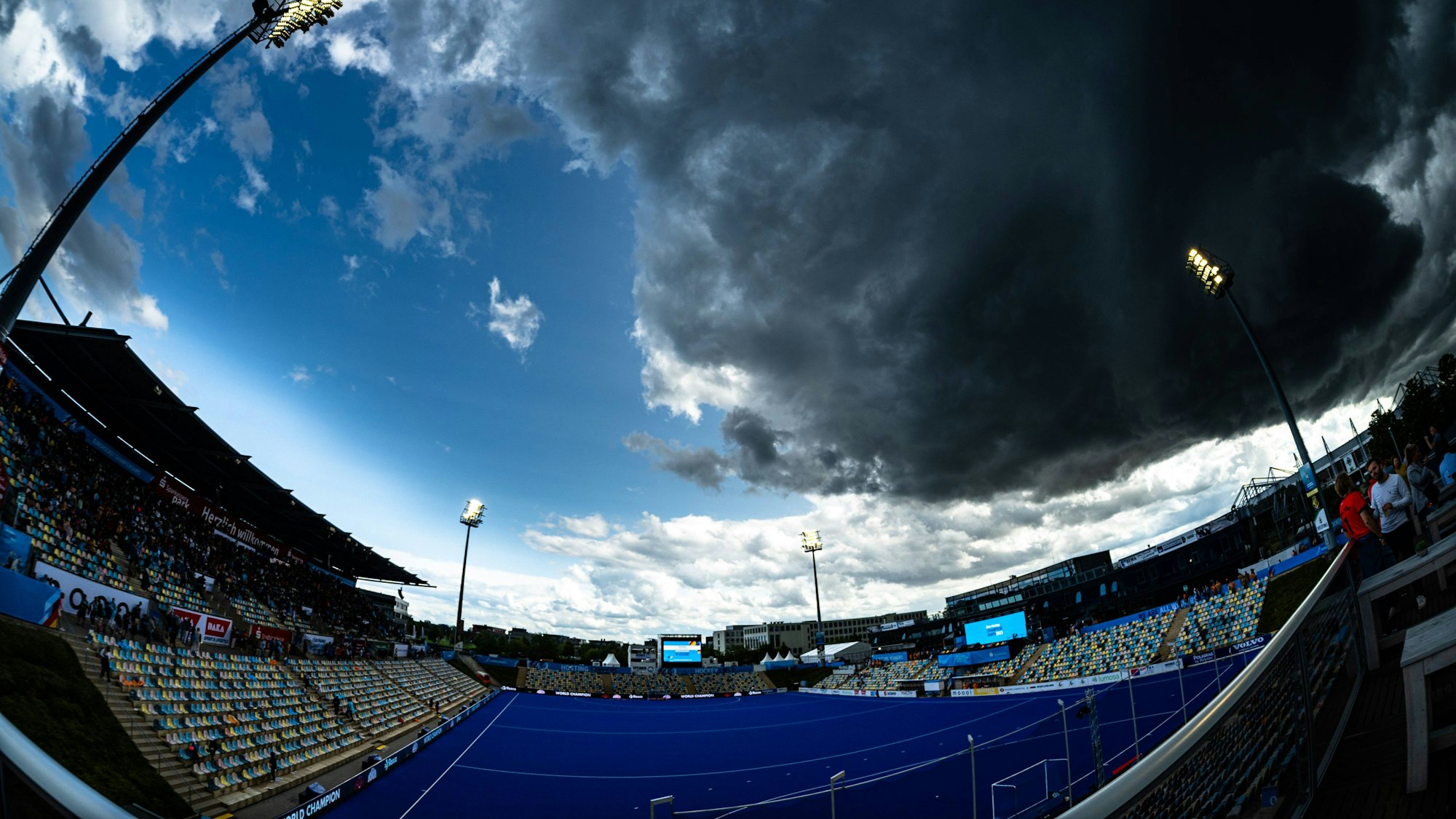 Der Hockey Park Deutschland in Mönchengladbach ist aus einer Ecke heraus zu sehen. Am Himmel ziehen graue Unwetterwolken auf.