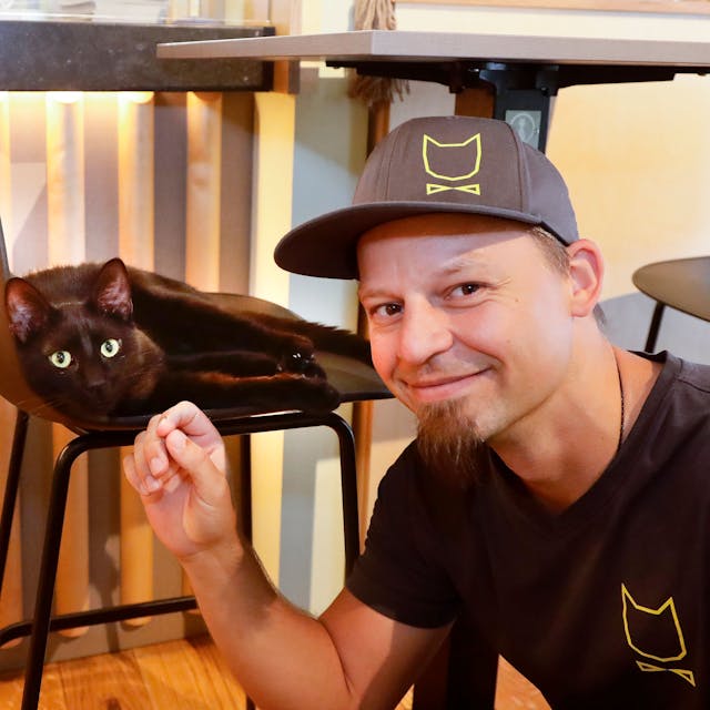 Michael Guddat, Tierpsychologe, Katzensitter und Katzenexperte, mit einer schwarzen Katze im Café Katzentempel in der Kölner Severinstrasse.