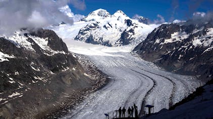 ARCHIV - 14.06.2023, Schweiz, Goms: Menschen genießen die Aussicht auf den Aletschgletscher in der Nähe von Goms.  Die Schweizer Gletscher haben nach 2022 ein zweites Extremjahr erlebt. In beiden Jahren zusammen ist das Gletschervolumen um zehn Prozent geschrumpft, wie die Schweizerische Kommission für Kryosphärenbeobachtung der Akademie der Naturwissenschaften am Donnerstag berichtete. (zu dpa: «Zweites Extremjahr für Schweizer Gletscher») Foto: Matthias Schrader/AP +++ dpa-Bildfunk +++