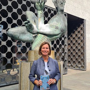Autorin Petra Sophia Zimmermann präsentiert ihr neues Buch vor dem Baptisterium am Kölner Dom.