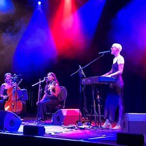Drei Musikerinnen auf einer Bühne am Keyboard, Geige und Cello.