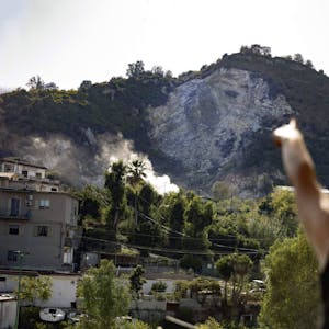 Eine Frau zeigt in Neapel in Richtung von Rauch, der über den Phlegräischen Feldern nahe der Stadt aufsteigt. Nach dem stärksten Erdbeben seit 40 Jahren steigen die Sorgen um einen Ausbruch von Europas Supervulkan.