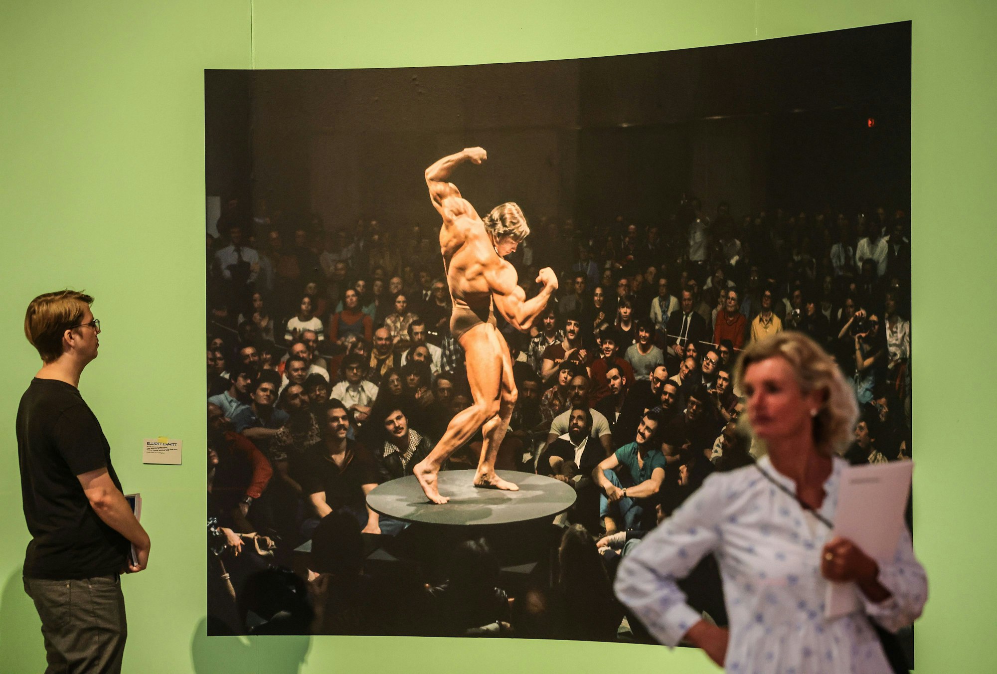 28.09.2023, Nordrhein-Westfalen, Bonn: Ausstellungsbesucher gehen an einer Fotografie von Elliott Erwitt vorbei, die Arnold Schwarzenegger zeigt. Die Ausstellung ·Alle auf einmal: Die Postmoderne, 1967·1992· ist vom 29.09.2023 bis zum 28.01.2024 in der Bundeskunsthalle zu sehen.