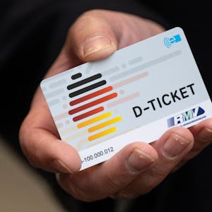 Eine Person hält ein Deutschland-Ticket in der Hand.