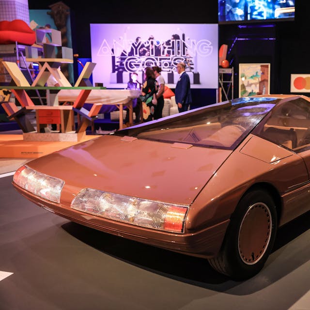 Das Konzeptfahrzeug "Citroen Karin" aus dem Jahr 1980 steht in der Bundeskunsthalle. Es ist rötlich und geometrisch-schnittig. Im Hintergrund weitere bunte Kunstwerke und Besucher.&nbsp;