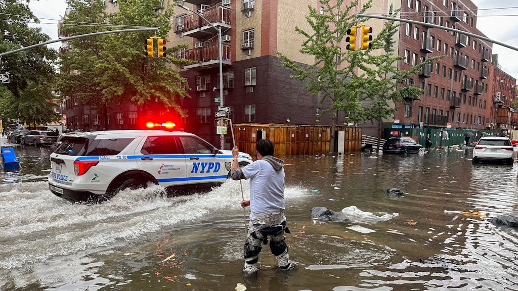 Ein Mann versucht am Freitag (29. September 2023) im Stadtbezirk Brooklyn (New York) einen Abfluss im Hochwasser zu reinigen. Heftiger Regen hat in der Millionenmetropole New York zu Überschwemmungen und Sperrungen von Autobahnen, Straßen und Flughafenterminals geführt.