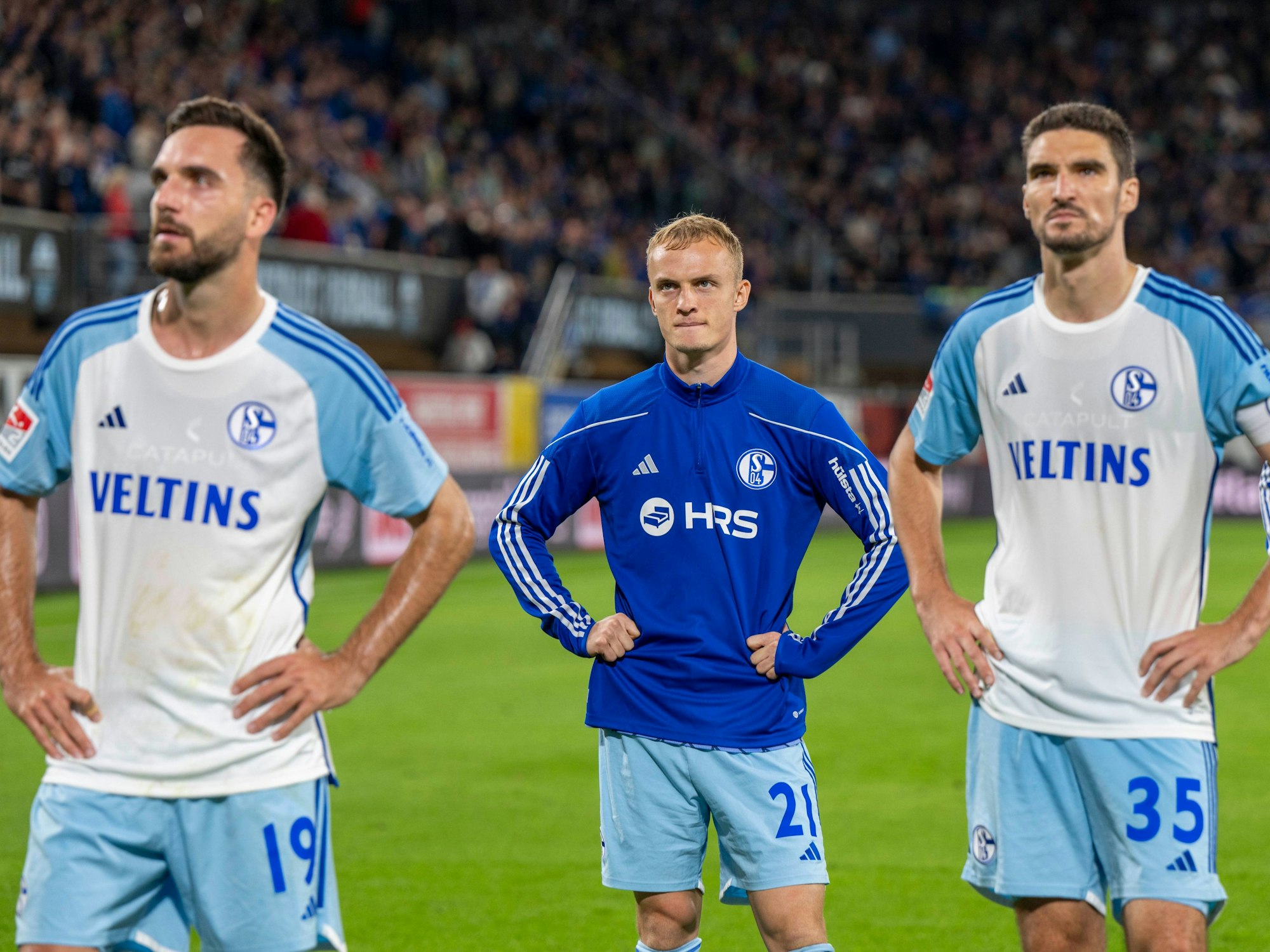 Kenan Karaman (v.li.), Niklas Tauer und Marcin Kaminski stehen nach der Schalke-Niederlage in Paderborn enttäuscht vor den Fans.