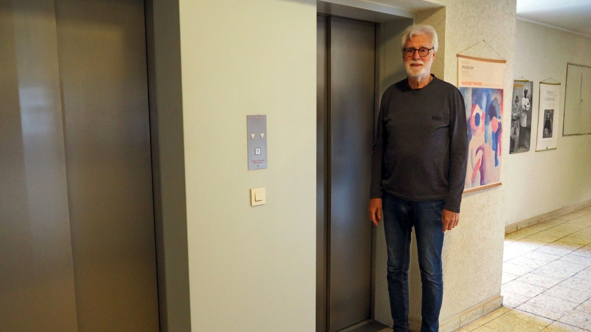 Ein Mann steh zwischen zwei Aufzügen.
