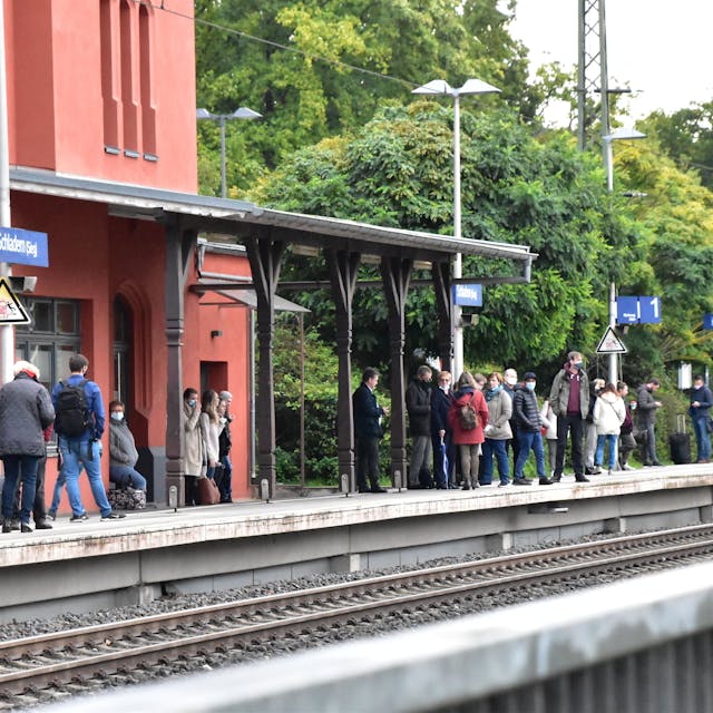 Reisende warten auf einem Bahnsteig auf den Zug.