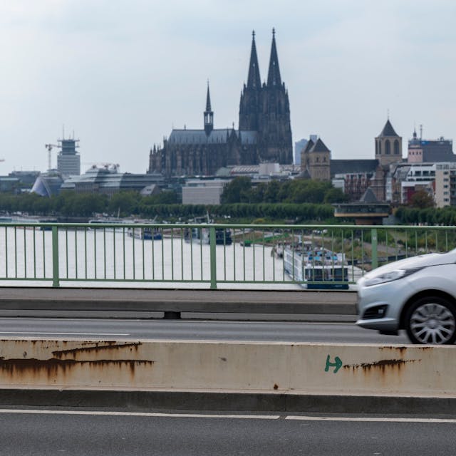 Ein Auto fährt über die Zoobrücke in Köln, im Hintergrund ist der Kölner Dom zu sehen.