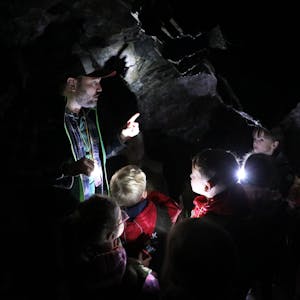 Ein Mann steht mit Kindern in einer Höhle.