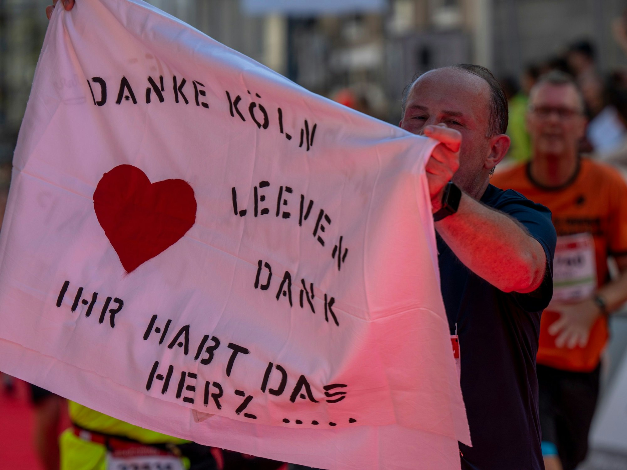 Ein Mann hält ein Stück Stoff, auf dem steht „Danke Köln“.