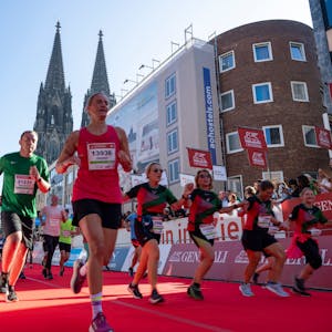 Glück beim Zieleinlauf: Teilnehmerinnen und Teilnehmer erreichen das Ende des Köln Marathons im Schatten des Kölner Doms.
