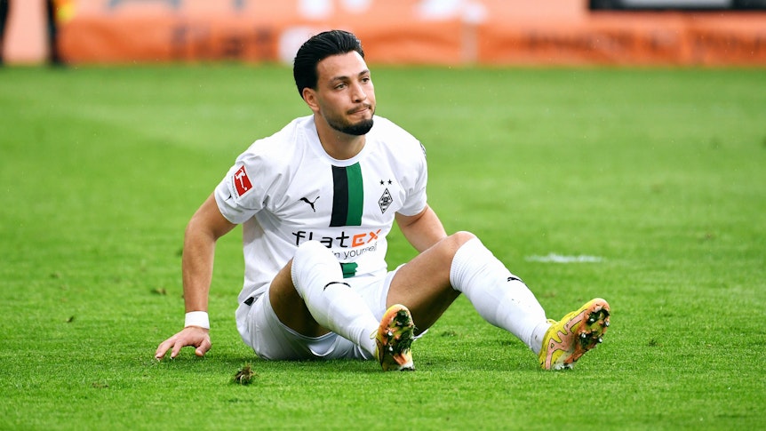 Ramy Bensebaini sitzt auf dem Boden.