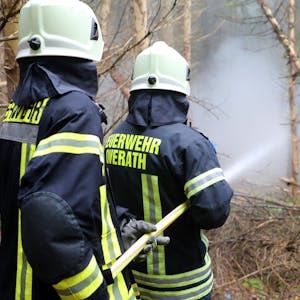 Zwei Feuerwehrleute der Feuerwehr Overath halten einen C-Schlauch auf Übungsrauch in einem Fichtenwald.