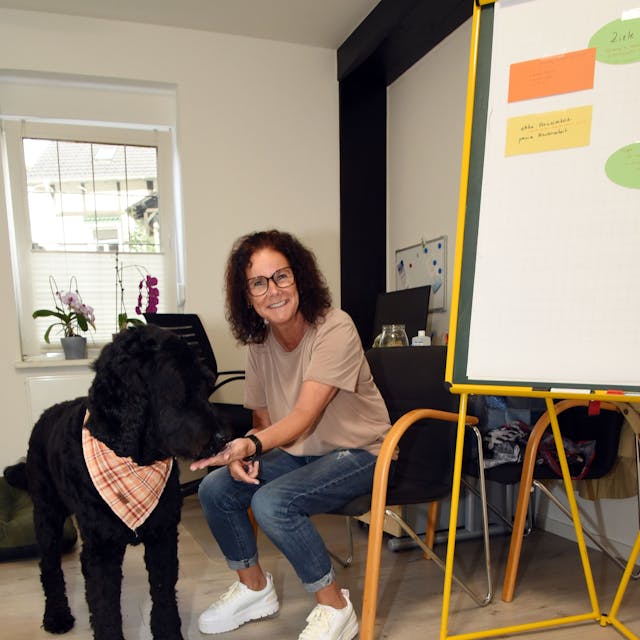 Das Foto zeigt Therapeutin Jutta Schüler und ihren schwarzen Hund Gunnar.