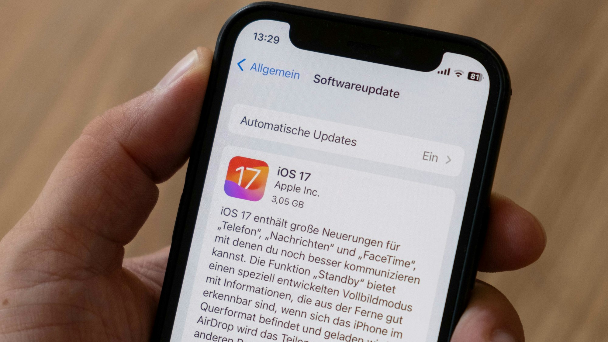 Eine Hand hält ein iPhone, auf dem Bildschirm sieht man das Software-Update iOS 17.