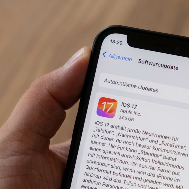 Eine Hand hält ein iPhone, auf dem Bildschirm sieht man das Software-Update iOS 17.