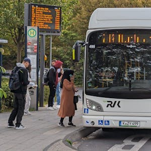 Ein Bus an einer Bushaltestelle in Hürth-Hermülheim, an der Fahrgäste warten.