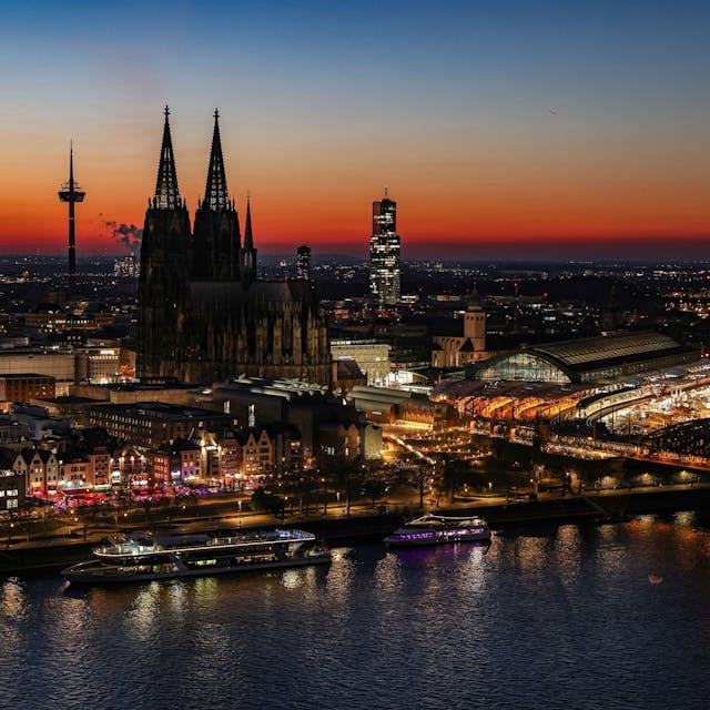Der Himmel färbt sich hinter dem Rheinpanorama mit Dom (M.) und Hauptbahnhof (r.) nach Sonnenuntergang rötlich.