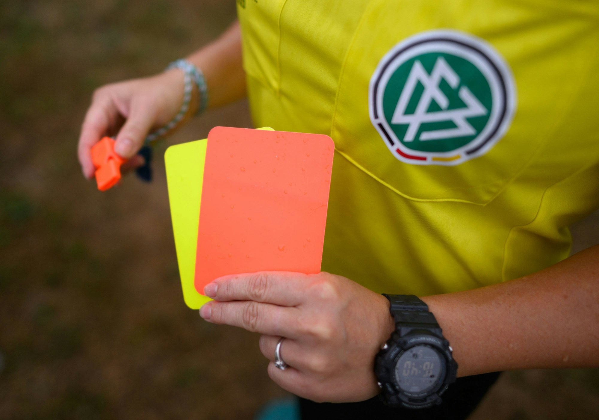 Eine Schiedsrichterin zeigt eine Rote und eine Gelbe Karte.