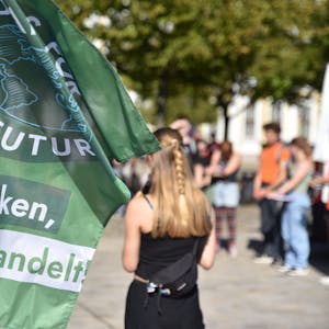 Eine Rednerin spricht zum „Klimastreik“ von Fridays for Future auf dem Domplatz in Magdeburg. Im Vordergrund ist eine Flagge der Klimaaktivisten