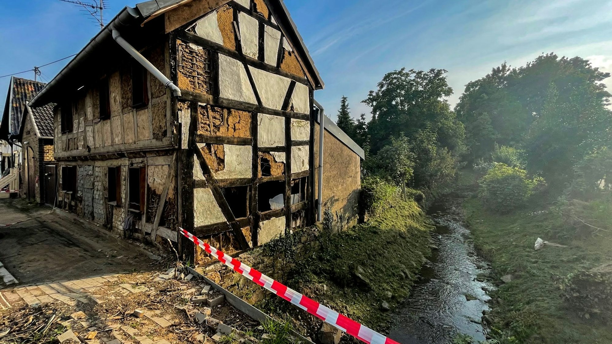 Das Bild zeigt ein zerstörtes Fachwerkhaus neben dem Steinbach mitten in Schweinheim.