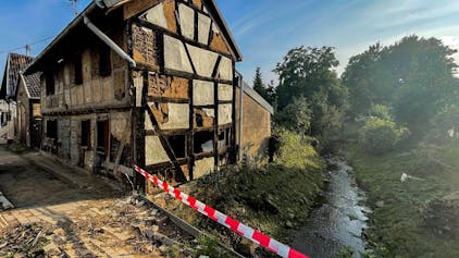 Das Bild zeigt ein zerstörtes Fachwerkhaus neben dem Steinbach mitten in Schweinheim.