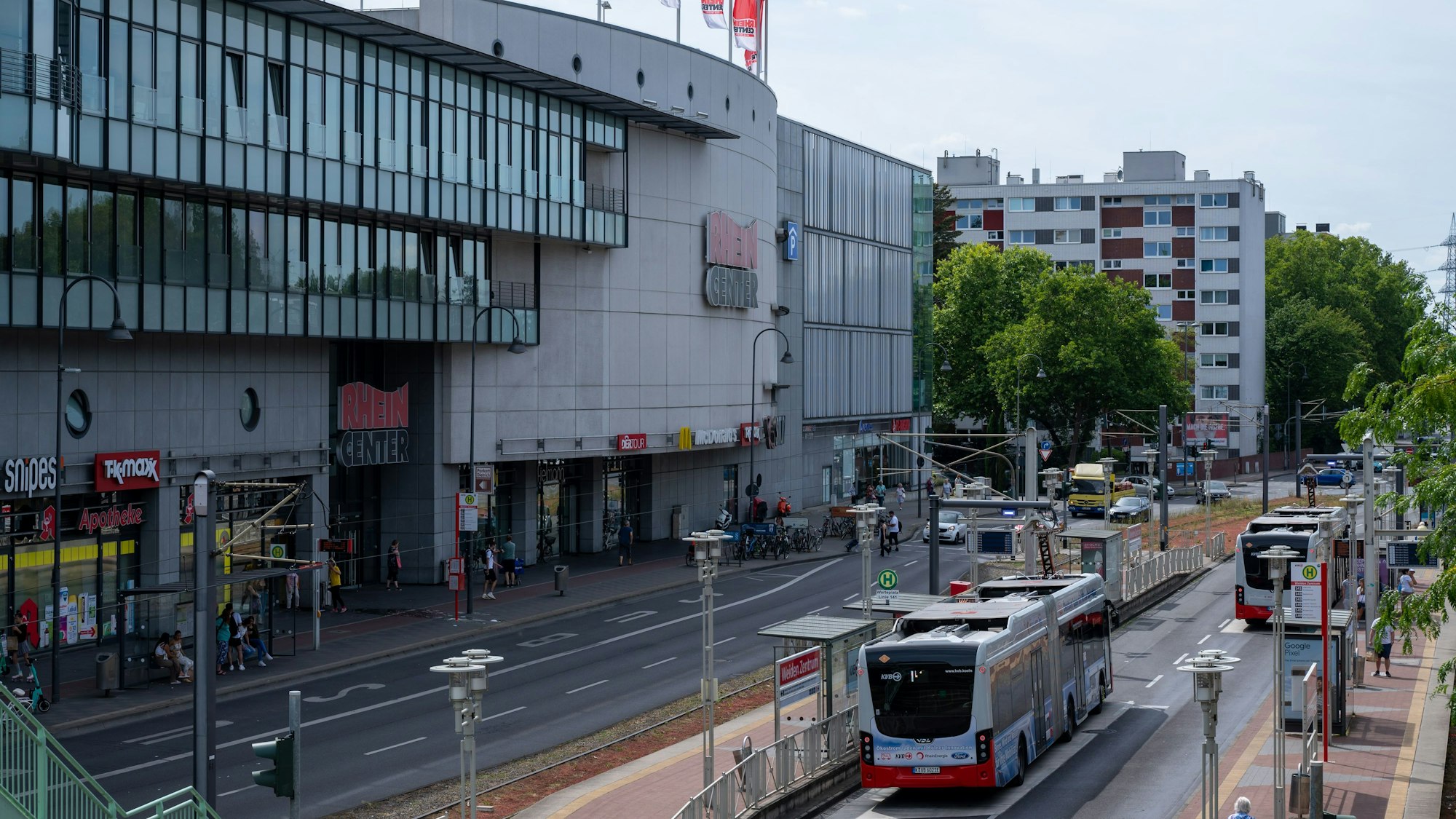 Blick auf das Einkaufszentrum Rhein-Center in Weiden. Im Vordergrund ist der Straßenverkehr mit Autos und Bussen zu sehen.