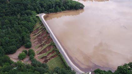 Das Bild zeigt die Steinbachtalsperre nach der Flut. Auf der Luftseite des Damms ist viel Erdreich abgerutscht.