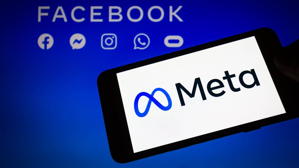 Das Logo von Meta, der Dachmarke des Facebook-Konzerns, wird auf einem Smartphone angezeigt, im Hintergrund sind die Logos von Facebook, Messenger, Instagram, Whatsapp und Oculus zu sehen.