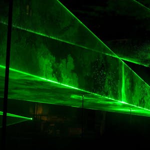 Grüne Laserstrahlen bilden treppenartige Strukturen in der Dunkelheit.&nbsp;