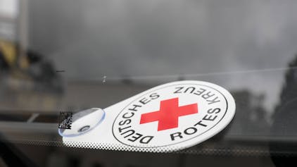 Autoschild Deutsches Rotes Kreuz liegt hinter der Frontscheibe eines Fahrzeuges des Katastrophenschutzes.