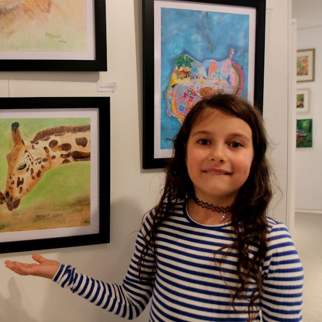 Ein Mädchen zeigt auf ein Bild, auf dem Giraffen zu sehen sind.&nbsp;